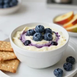 - 8 oz cream cheese, softened - 1/2 cup sour cream - 1/2 cup powdered sugar - 1 teaspoon pure vanilla extract - 1 cup fresh blueberries (plus extra for garnish) - 1 tablespoon fresh lemon juice - 1/4 teaspoon ground cinnamon - Assorted graham crackers, cookies, or fresh fruit for dipping For the cream cheese, use a low-fat version if you want, but regular gives the best taste. Sour cream can be swapped with plain Greek yogurt for a tangy twist. If you don&rsquo;t have powdered sugar, you can blend regular sugar until fine. For vanilla extract, try almond extract for a different flavor. Fresh blueberries are ideal, but frozen ones work in a pinch. Just make sure to thaw them first. This dip serves about 6-8 people. Each serving has roughly: - Calories: 210 - Fat: 15g - Carbohydrates: 17g - Protein: 3g - Fiber: 1g This dip is a sweet treat but still has some nutritional benefits from the blueberries, which are high in antioxidants. Enjoy in moderation! {{ingredient_image_2}} Start with 8 oz of softened cream cheese. Place it in a medium bowl. Beat it with an electric mixer on medium speed. Mix until it is smooth and creamy, with no lumps. This step is key for a nice dip. Next, add 1/2 cup of sour cream. Then, add 1/2 cup of powdered sugar and 1 teaspoon of pure vanilla extract. Keep mixing until the mix is velvety and well combined. Now, take 1 cup of fresh blueberries. Mash half of them in a small bowl with a fork. Leave some chunks for texture. Mix in 1 tablespoon of fresh lemon juice and 1/4 teaspoon of ground cinnamon. Stir until it&rsquo;s blended well. This blueberry mix adds a fruity burst to your dip. Gently fold the mashed blueberry mix into the cream cheese base. Use a spatula to create swirls. Be careful not to overmix; you want to keep those pretty swirls. Now, transfer the dip into a nice serving bowl. For a lovely touch, add the reserved blueberries on top for garnish. Serve it right away with graham crackers, cookies, or fresh fruit. Enjoy this creamy and fruity delight! To get a smooth dip, start with softened cream cheese. Cold cream cheese will not mix well. Beat it well until it is creamy and lump-free. Mix in sour cream and powdered sugar next. This adds creaminess and sweetness. Make sure to blend until it is velvety. Avoid overmixing at the end to keep some of the blueberry texture. For a tasty twist, add a hint of lemon juice. It brightens the flavors and balances the sweetness. You can also try a pinch of ground cinnamon. This adds warmth and depth to the dip. If you want more blueberry flavor, fold in more mashed blueberries. Feel free to experiment with flavors you enjoy. Serve the dip in a pretty bowl for a great look. Top it with fresh blueberries for color. Pair the dip with graham crackers, cookies, or fresh fruit. Try strawberries or apple slices for something different. This dip is perfect for parties or as a fun snack at home. Enjoy every creamy bite! Pro Tips Use Room Temperature Ingredients: Ensuring your cream cheese and sour cream are at room temperature will make it easier to achieve a smooth and creamy dip without lumps. Fresh vs. Frozen Blueberries: For the best flavor and texture, always opt for fresh blueberries. If using frozen, make sure to thaw and drain them well to avoid excess moisture. Customize Your Sweetness: Adjust the amount of powdered sugar to suit your taste. If you prefer a less sweet dip, start with less sugar and add more if needed. Presentation Matters: For an appealing presentation, serve the dip in a decorative bowl and garnish with extra blueberries and a sprinkle of cinnamon on top. {{image_4}} You can change up the fruit in this dip. Instead of blueberries, try strawberries, raspberries, or diced peaches. Each fruit brings a new taste. You can also mix in nuts or coconut for added crunch. If you like a bit of spice, add a touch of nutmeg or ginger. Toppings can make your dip extra special. Try crushed graham crackers for a crunchy layer. You can also sprinkle some chocolate chips or mini marshmallows on top. Fresh mint leaves add color and a burst of flavor. Get creative with your toppings to match your taste. To make this dip gluten-free, use gluten-free graham crackers or cookies. Fresh fruit is a great choice too. You can even use gluten-free pretzels for a salty twist. Always check labels to ensure your ingredients are gluten-free. This way, everyone can enjoy this tasty treat! After enjoying your Blueberry Cheesecake Dip, store any leftovers in an airtight container. This keeps the dip fresh and tasty. Make sure to cover it well to avoid drying out. You can also wrap the bowl tightly with plastic wrap if needed. This dip tastes best when served cold. If your dip seems a bit thick after storage, mix in a splash of sour cream or cream cheese. Stir it well to regain that creamy texture. Avoid heating it in the microwave, as it may change the flavor. You can store the Blueberry Cheesecake Dip in the fridge for up to 3 days. After that, the freshness may fade. Always check for any off smells or changes in texture before enjoying it again. Yes, Blueberry Cheesecake Dip can be gluten-free. The main dip ingredients, like cream cheese and sour cream, are gluten-free. To keep it gluten-free, use gluten-free graham crackers or fruit for dipping. You can make this dip ahead of time. It stays fresh in the fridge for up to two days. Just cover it well to keep it from drying out. Serve it chilled for the best taste. You have many options for dipping! Try using cookies, fresh fruit like strawberries or apple slices, or even pretzels. Each adds a fun twist to the tasty dip. Yes, you can use frozen blueberries! Just thaw them before mashing. Keep in mind that frozen berries may be more watery. This might change the dip's texture slightly. This blog post covered how to make a tasty Blueberry Cheesecake Dip. We looked at the key ingredients, like cream cheese and blueberries, and shared helpful tips for the best texture and taste. You learned about fun variations and storage tips, so your dip stays fresh. In conclusion, I hope you feel ready to try this easy recipe. Enjoy experimenting with flavors and toppings to make it your own!